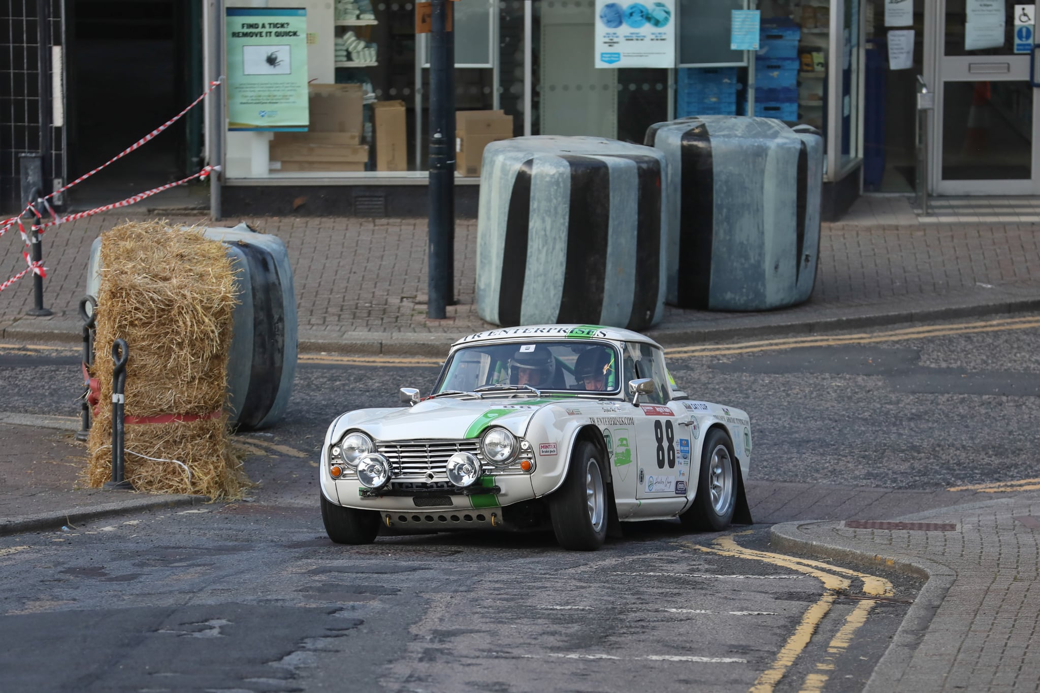 Classic rally car navigating a street corner during a historic rally event.